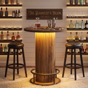 May include: A round wooden bar table with a central illuminated pedestal and a metal footrest, flanked by two black tufted bar stools. A sign above reads The Barkeep's Nook - EST. 2023. The table holds a glass decanter, two glasses, and a metal cocktail shaker.