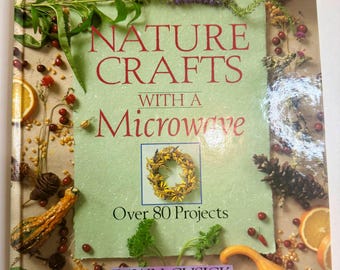 May include: A book titled "Nature Crafts with a Microwave" with the author's name, Dawn Cusick. The cover features the title in red and a green background. The cover is decorated with various natural elements, including gourds, berries, and orange slices.