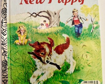 May include: A Little Golden Book titled The New Puppy, number 303-55. The cover features a brown and white puppy holding a stick in a green field with two children, a tree, and a silver spine with a black floral pattern. A price sticker is visible.