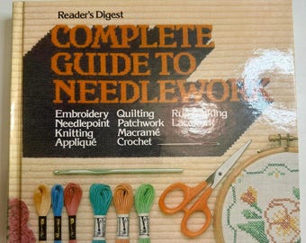 May include: A vintage "Reader's Digest Complete Guide to Needlework" book. The cover features the title in orange and black, with various needlework techniques listed. Includes embroidery floss, scissors, a crochet hook, and an embroidery hoop.