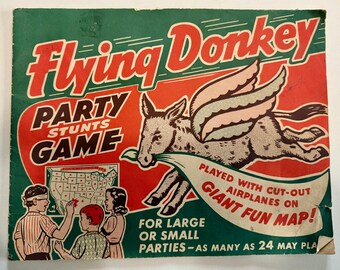 May include: Vintage board game box titled "Flying Donkey Party Stunts Game." The box features a cartoon donkey with wings, a map of the United States, and children playing. The text reads "Played with cut-out airplanes on giant fun map!"