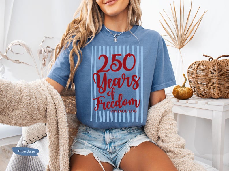 Woman wearing blue jean Comfort Colors patriotic shirt featuring “250 Years of Freedom Vintage 1776” retro red and blue design for Fourth of July celebration