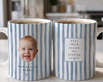 May include: Two white ceramic mugs with blue vertical stripes. The left mug features a photo of a baby and the text "good morning daddy!" with a heart. The right mug features a square box with the text "Your third reason for needing coffee" and a heart.