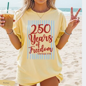 Woman wearing butter Comfort Colors patriotic shirt featuring “250 Years of Freedom Vintage 1776” retro red and blue design for Fourth of July celebration
