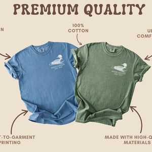 May include: Two t-shirts, one blue and one green, with a white graphic of a duck and the text "STUDIO CAROLINAS GOLF CLUB 2020". The shirts are made of 100% cotton and are ultra comfortable. The shirts are printed in the USA.