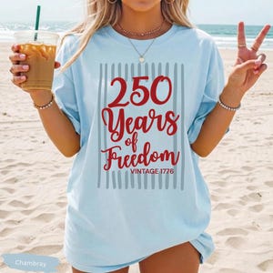 Woman wearing chambray Comfort Colors patriotic shirt featuring “250 Years of Freedom Vintage 1776” retro red and blue design for Fourth of July celebration