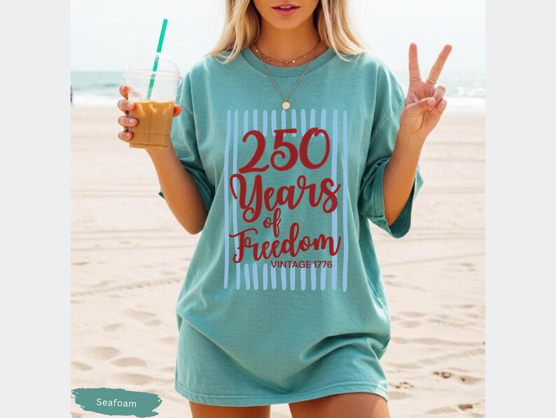 Woman wearing seafoam Comfort Colors patriotic shirt featuring “250 Years of Freedom Vintage 1776” retro red and blue design for Fourth of July celebration