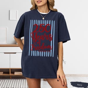 Woman wearing navy Comfort Colors patriotic shirt featuring “250 Years of Freedom Vintage 1776” retro red and blue design for Fourth of July celebration
