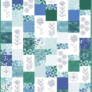 May include: A patchwork quilt featuring a floral design. The quilt is composed of various squares in shades of blue, green, and white. Some squares have embroidered flower outlines, while others have geometric patterns or floral prints. The quilt has a green border.