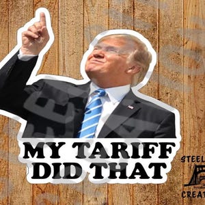 May include: A sticker featuring a photo of a man in a suit with his arm raised, pointing upwards. The text "MY TARIFF DID THAT" is printed in black on a white background. The sticker also includes a logo for "Steel City Creations".