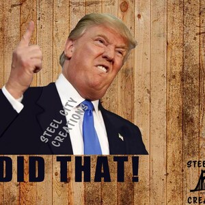 May include: A man in a dark suit and blue tie points his finger upwards and says "I DID THAT!" with a serious expression. The background is a wood grain pattern. The text "STEEL CITY CREATIONS" is visible in the image.