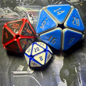 May include: Three polyhedral dice in red, blue, and white. The red die has black numbers, the blue die has white numbers, and the white die has blue numbers. Each die has a different number of sides, ranging from 10 to 20.