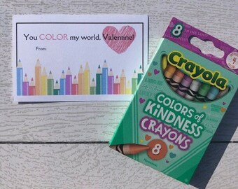 Op de afbeelding: Een Valentijnskaart met een hart en de tekst "You COLOR my world, Valentine!" met een rij kleurpotloden eronder. Een doos met 8 Crayola Colors of Kindness kleurpotloden is ook te zien.