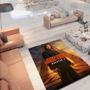 Puede incluir: Una alfombra rectangular con el cartel de la película "John Wick: Capítulo 4". La alfombra muestra a un hombre con un traje negro con el título de la película en naranja y amarillo sobre un fondo de un edificio y una puesta de sol.
