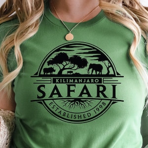 May include: A green t-shirt with a black graphic design of a safari scene with the text "Kilimanjaro Safari Established 1998".