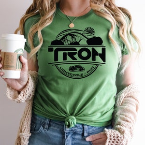 May include: Green t-shirt with a black circle graphic featuring the word "TRON", a lightcycle, and the text "LIGHTCYCLE / RUN".