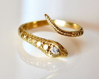 May include: A gold snake ring with a single diamond set in the head. The snake is coiled around the finger and has a textured body.
