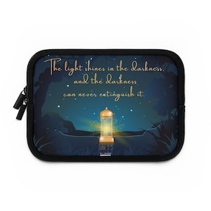 May include: A black laptop sleeve featuring a night scene with a glowing lantern and the text "The light shines in the darkness, and the darkness can never extinguish it." The design includes a starry sky and forest silhouettes.