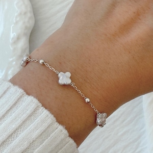 May include: A silver chain bracelet with three white baroque pearls. The pearls are irregular in shape and have a natural, organic look.