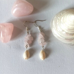 Può includere: Un paio di orecchini con ciottoli di quarzo rosa e ciondoli di conchiglia bianca. Gli orecchini sono appesi a ganci d'argento.