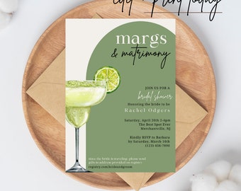 Puede incluir: Una invitación a una despedida de soltera con una ilustración de margarita. La invitación presenta el texto "margs & matrimony" y los detalles del evento. El diseño incluye una rodaja de lima y está sobre una bandeja de madera con un sobre de papel kraft.