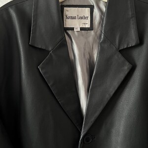 Peut inclure: Un blazer en cuir noir avec un revers crant&eacute; et une fermeture &agrave; un seul bouton. La doublure int&eacute;rieure est de couleur gris clair. L'&eacute;tiquette indique "The Keenan Leather company" et la taille est XL.