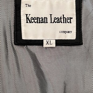 Peut inclure: &Eacute;tiquette en cuir noir avec le texte "The Keenan Leather company" et une &eacute;tiquette de taille "XL". L'&eacute;tiquette est cousue sur un tissu &agrave; rayures noires et blanches.