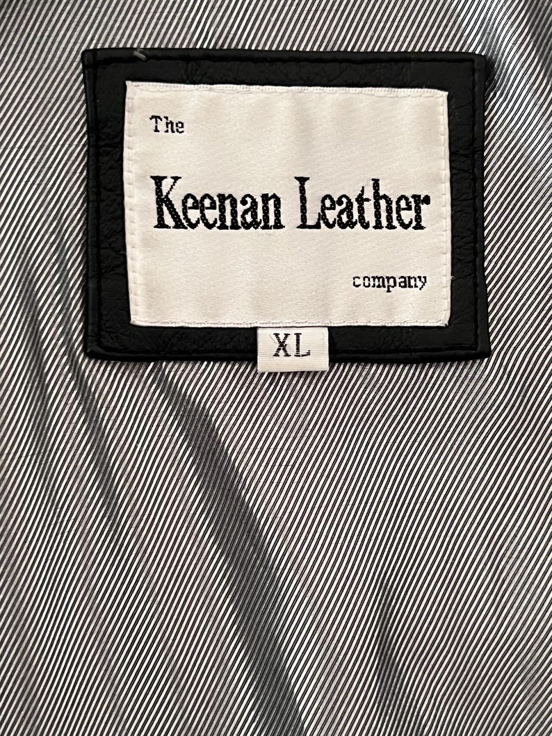 Peut inclure: &Eacute;tiquette en cuir noir avec le texte "The Keenan Leather company" et une &eacute;tiquette de taille "XL". L'&eacute;tiquette est cousue sur un tissu &agrave; rayures noires et blanches.