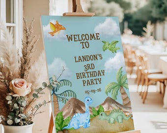 May include: A rectangular birthday party welcome sign on a wooden easel featuring a light blue sky background with white clouds, brown mountains, palm trees, and cartoon dinosaurs. The text reads: WELCOME TO LANDON'S 3RD BIRTHDAY PARTY 05-09-26.