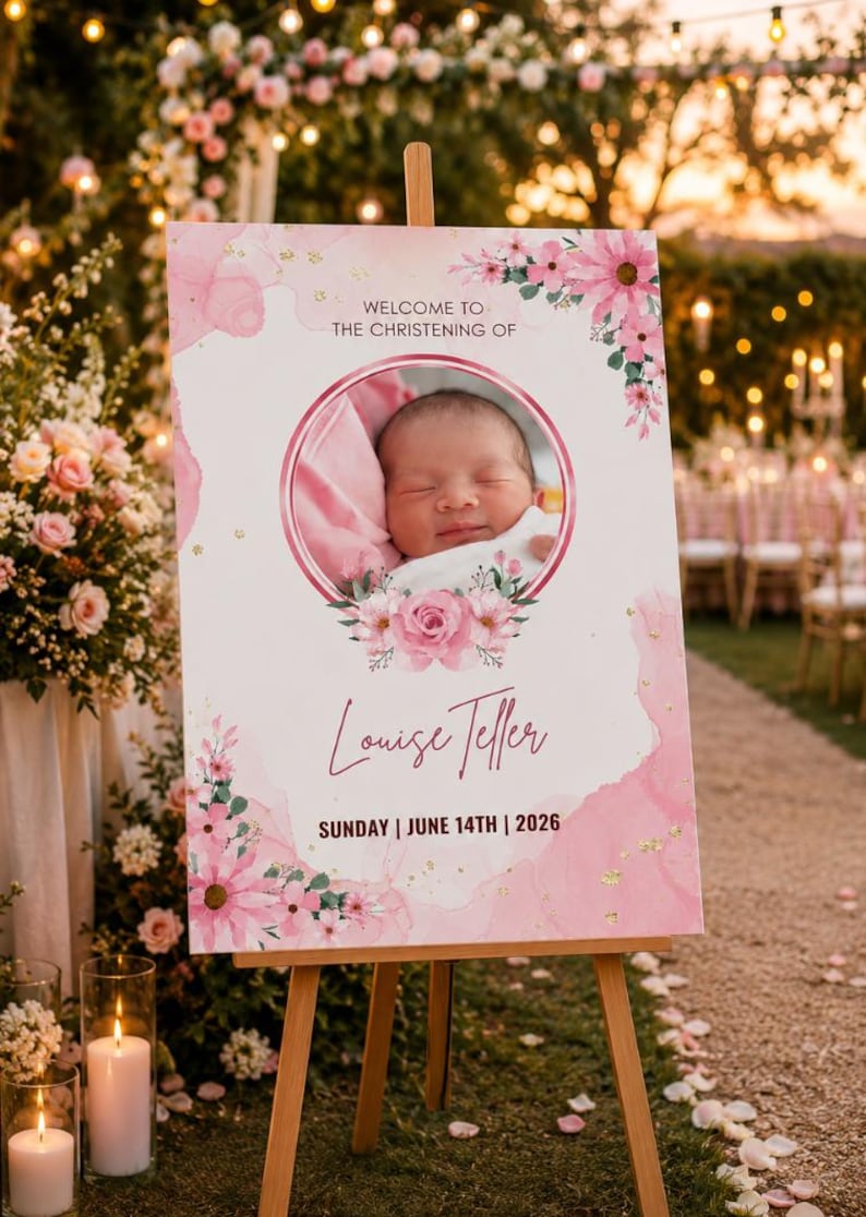 May include: A pink and white christening sign on a wooden easel. The sign displays "Welcome to the Christening of Louise Teller" and the date "Sunday | June 14th | 2026." A baby's photo is in the center, framed by floral decorations.