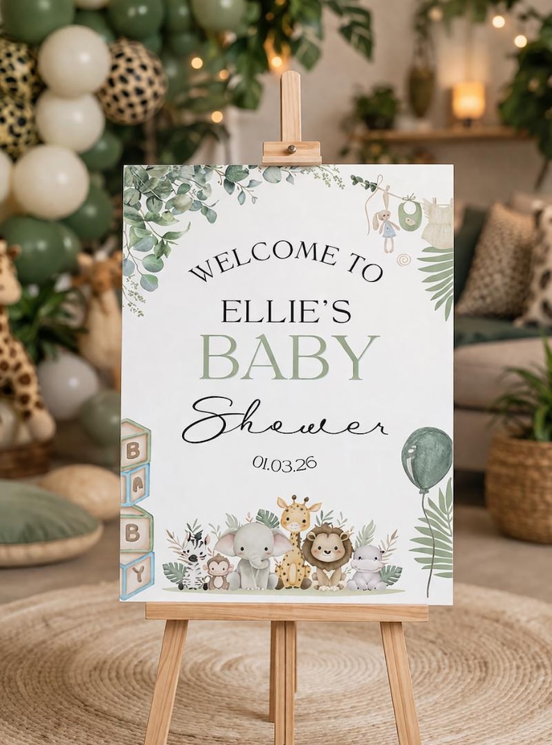 Pu&ograve; includere: Un cavalletto di legno espone un cartello per il baby shower con la scritta "Welcome to Ellie's Baby Shower 01.03.26." Il cartello presenta un design floreale verde e bianco e illustrazioni di animali per bambini. &Egrave; raffigurato anche un palloncino verde.