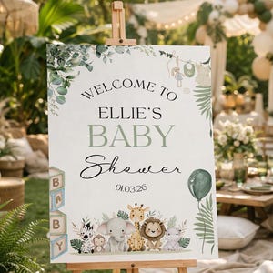 Pu&ograve; includere: Un cavalletto in legno espone un cartello per baby shower con la scritta "Welcome to Ellie's Baby Shower" e la data 01.03.26. Il cartello presenta illustrazioni di animali della giungla e vegetazione, con un palloncino verde.