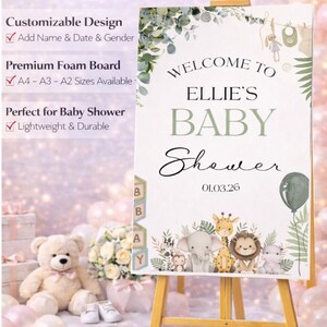 Pu&ograve; includere: Un cartello di benvenuto personalizzato per un baby shower su un cavalletto di legno. Il cartello recita "Benvenuti al Baby Shower di Ellie" con una data e illustrazioni di animali della savana. Decorato con verde e un palloncino.
