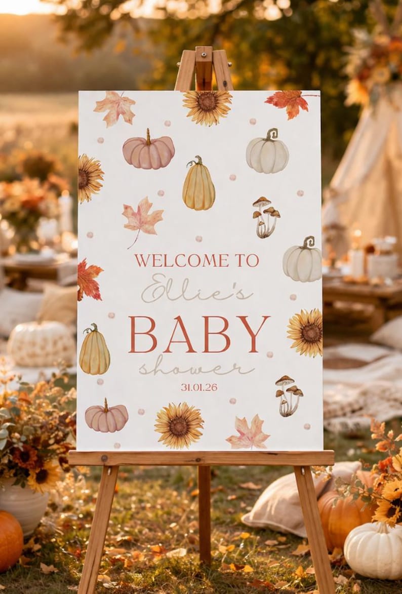 May include: A wooden easel displays a sign with a baby shower theme. The sign features watercolor illustrations of pumpkins, sunflowers, and leaves. Text reads "Welcome to Ellie's BABY shower 31.01.26."
