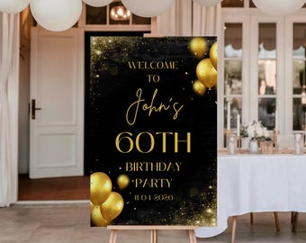 May include: A black and gold welcome sign for John's 60th birthday party. The sign features gold text and gold balloon graphics. The sign is displayed on a wooden easel, with white balloons and a party setting in the background.