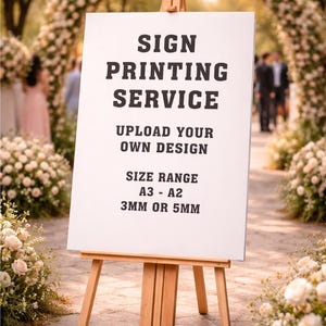 May include: A white sign on a wooden easel with the text "SIGN PRINTING SERVICE, UPLOAD YOUR OWN DESIGN, SIZE RANGE A3 - A2, 3MM OR 5MM". The sign is displayed outdoors, surrounded by floral arrangements and an archway.
