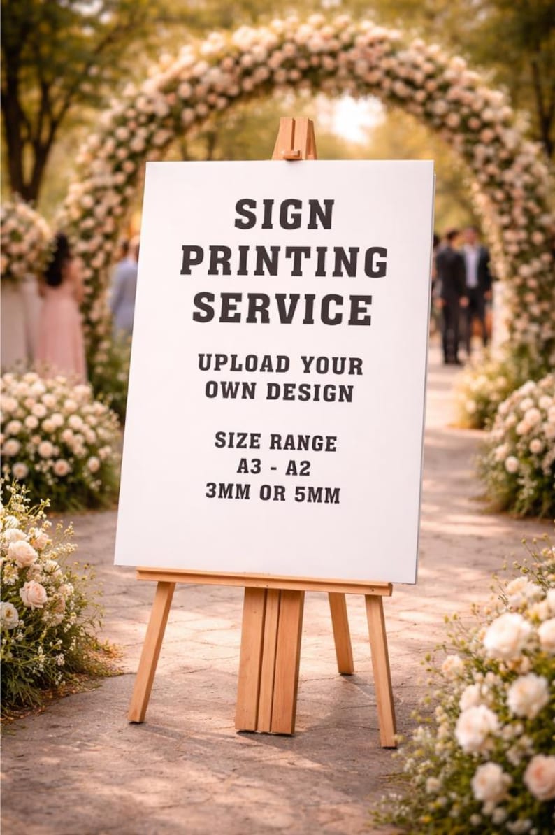 May include: A white sign on a wooden easel with the text "SIGN PRINTING SERVICE, UPLOAD YOUR OWN DESIGN, SIZE RANGE A3 - A2, 3MM OR 5MM". The sign is displayed outdoors, surrounded by floral arrangements and an archway.