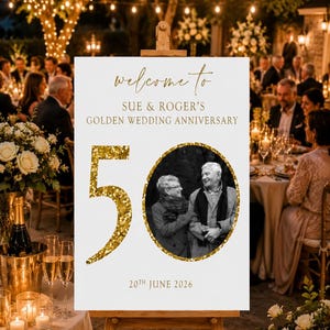 May include: A white sign on a wooden easel with gold text that reads "welcome to" and "SUE & ROGER'S GOLDEN WEDDING ANNIVERSARY". A photo of a couple is in a gold circle, with a large gold "50" and the date "20th JUNE 2026".