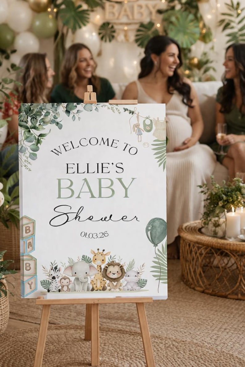 Pu&ograve; includere: Un cavalletto in legno espone un cartello di benvenuto per un baby shower. Il cartello recita "Welcome to Ellie's Baby Shower" con un design botanico e illustrazioni di animali per bambini. Sono presenti anche un palloncino verde e la data 01.03.26.