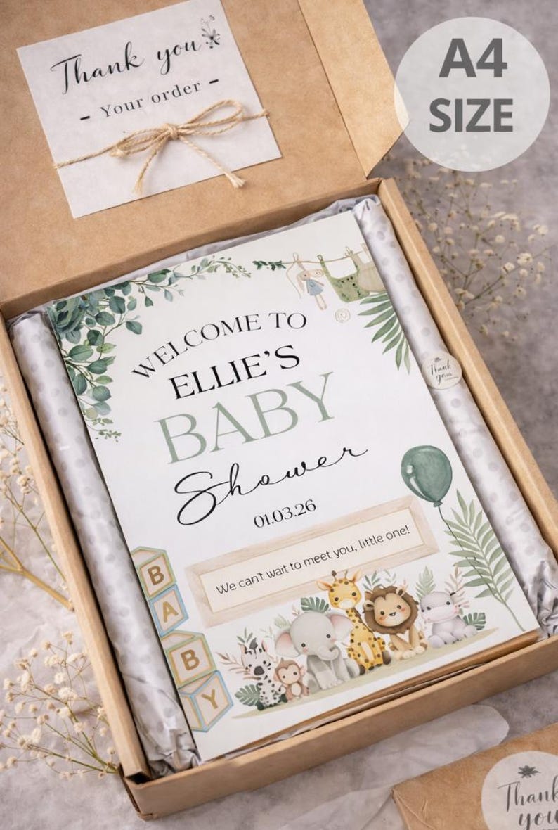 Pu&ograve; includere: Cartello per baby shower formato A4 in una scatola. Il cartello recita "Benvenuta al Baby Shower di Ellie" con la data 01.03.26. Il cartello ha una grafica a palloncino verde e un bordo di animali della giungla. La scatola include un biglietto "Grazie".