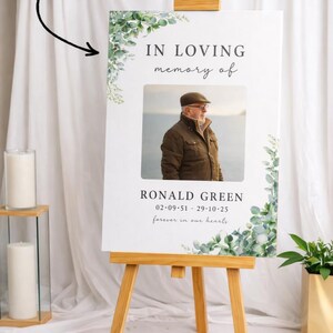 Peut inclure: Un chevalet en bois pr&eacute;sente un panneau comm&eacute;moratif avec le texte "IN LOVING memory of" et une photo d'un homme. Le panneau comprend le nom "RONALD GREEN" et des dates, encadr&eacute;s de verdure. Les mots "forever in our hearts" sont &eacute;galement pr&eacute;sents.