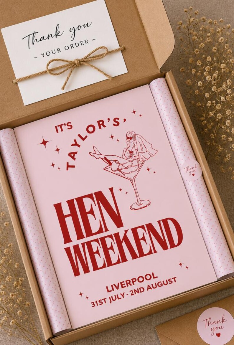 May include: A hen weekend gift box with a pink and red design. The box contains a pink poster with the text "IT'S TAYLOR'S, HEN WEEKEND" and a drawing of a woman in a martini glass. The box also includes a card that says "Thank you".