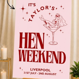 May include: A pink Hen Weekend sign on an easel. The sign has the text "IT'S TAYLOR'S, HEN WEEKEND, LIVERPOOL 31ST JULY - 2ND AUGUST" in burgundy. A drawing of a woman in a martini glass is also on the sign.