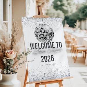 May include: A white sign on a wooden easel with the text "WELCOME TO Prom Night 2026" and a disco ball graphic. The sign has a silver glitter border and the school name "COTHAM SCHQOL" at the bottom.