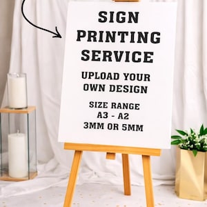 May include: A white sign on a wooden easel, advertising a sign printing service. The sign reads "SIGN PRINTING SERVICE, UPLOAD YOUR OWN DESIGN, SIZE RANGE A3 - A2, 3MM OR 5MM". A gold-colored "Custom Board" label is above the sign.