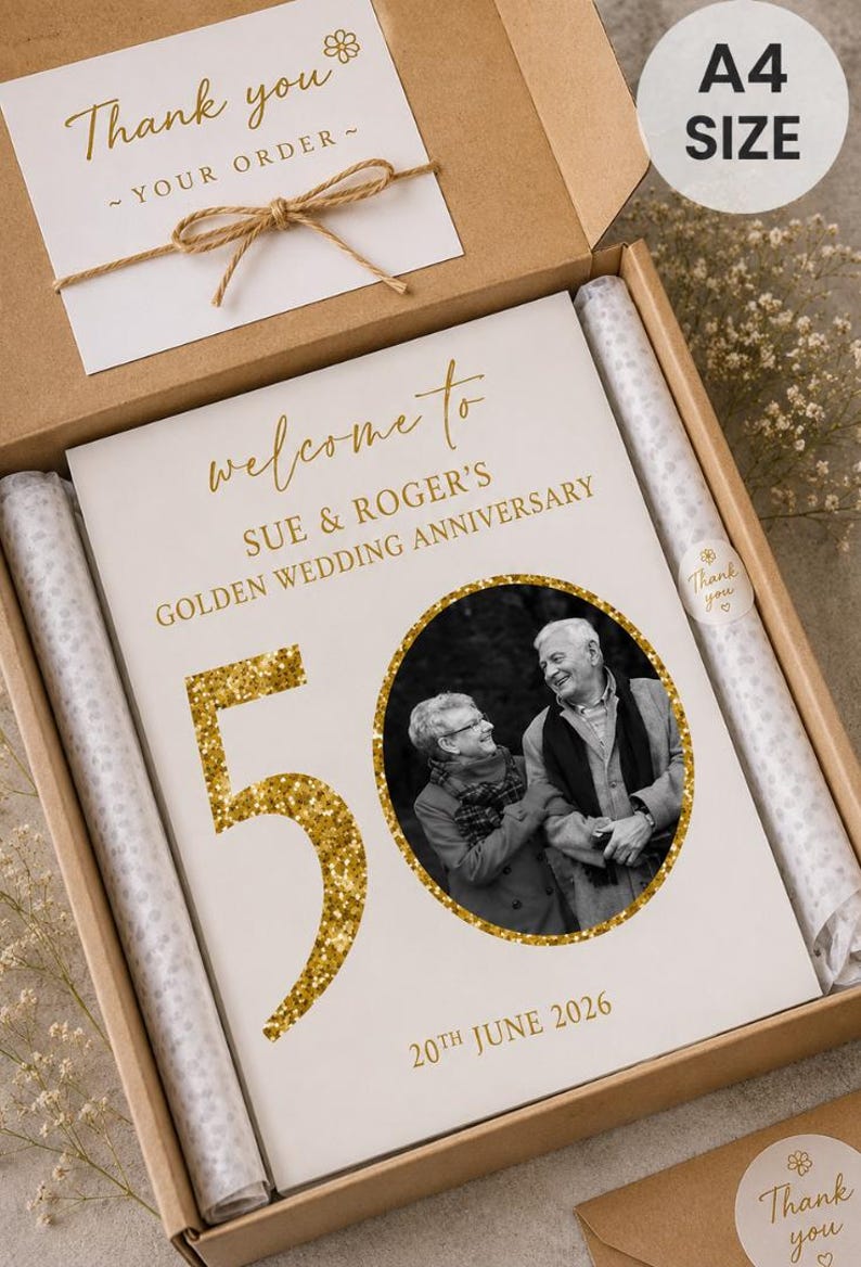 May include: A personalized golden wedding anniversary gift box. The box contains a card with the text "welcome to SUE & ROGER'S GOLDEN WEDDING ANNIVERSARY" and a photo of the couple. The number "50" is in gold glitter. The date "20th June 2026" is also included.