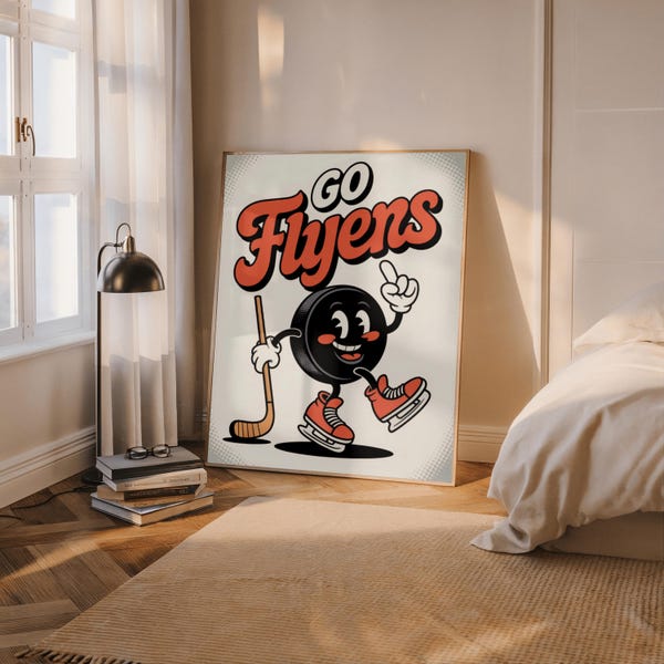 Puede incluir: Un póster enmarcado con un personaje de disco de hockey de dibujos animados con patines, un palo de hockey y las palabras "Go Flyers" en rojo y blanco. El disco sonríe y señala hacia arriba. El póster está en una habitación con una ventana y una cama.