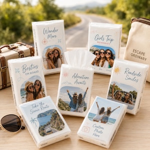 May include: A collection of white rectangular tissue packs featuring various travel-themed designs, custom photo prints, and blue text including phrases like Wander More, Besties On Board, Girls Trip Memories, Adventure Awaits, and Roadside Smiles.