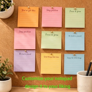 May include: A corkboard displays nine colorful sticky notes with motivational phrases like "You've got this" and "Stay positive." Each note is secured with a gold pushpin. The text "Customize your notepad design it to your liking" is at the bottom.