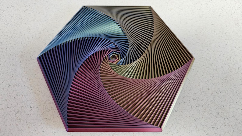 May include: A hexagonal geometric wall art piece made of metal with a swirling pattern of blue, purple, and gold colors.
